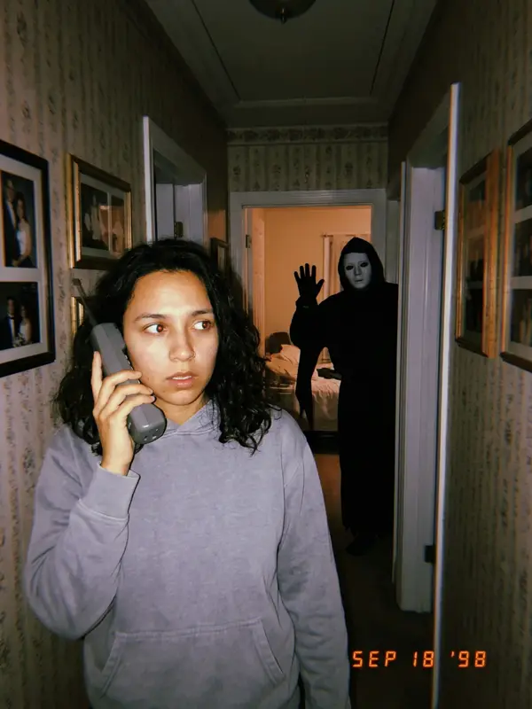Dark hallway with the masked figure waving at the far end