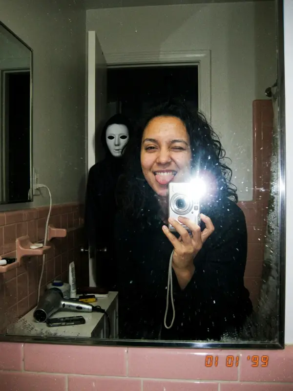 Mirror selfie with the masked figure behind in the dark